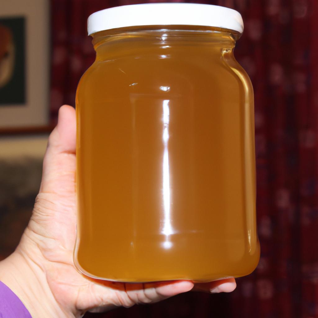 The weight of a 16 oz jar of honey being measured by hand